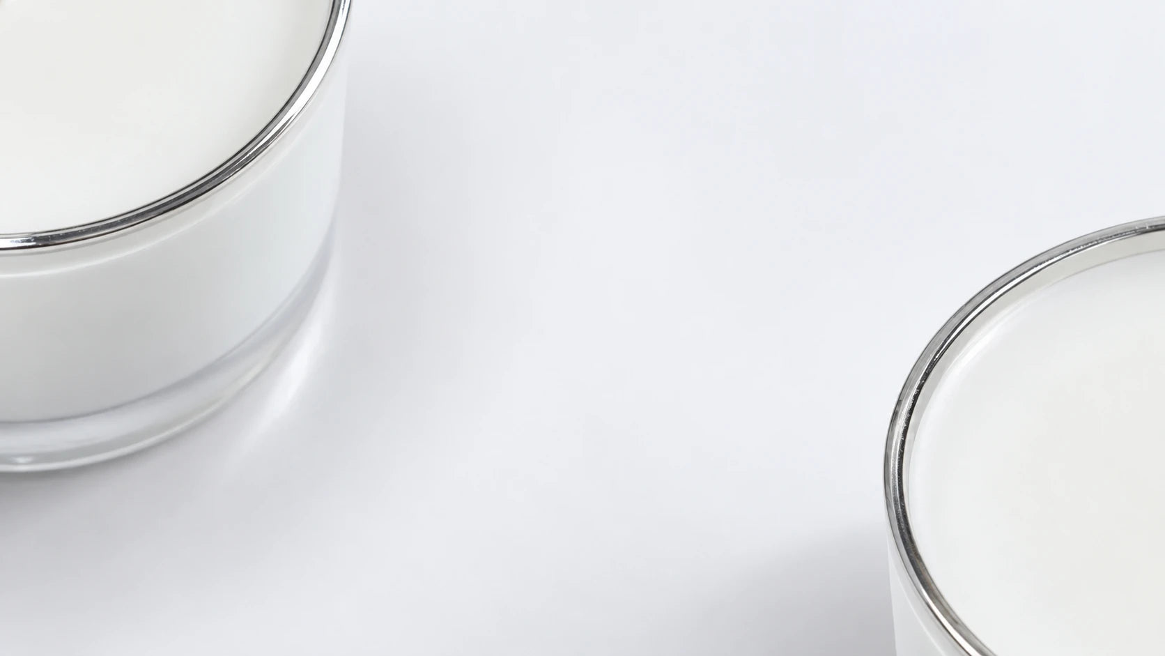 Oversized candle glass, silver rims and white wax around a quiet pale central field.