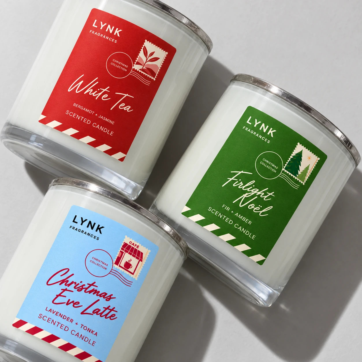 A close diagonal grouping of White Tea, Firlight Noël and Christmas Eve Latte Christmas candles.